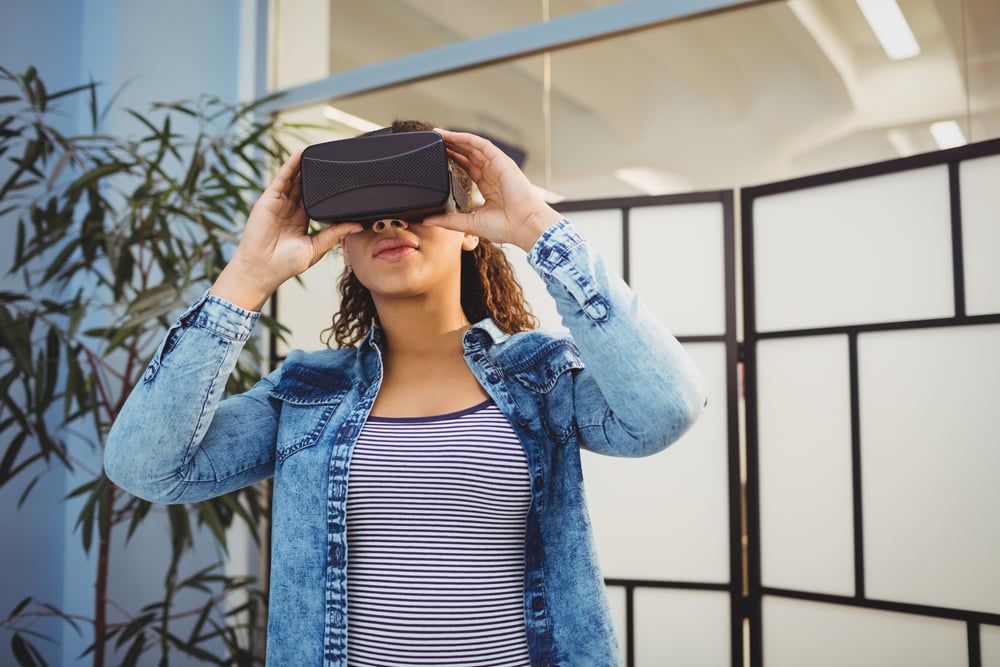 Low angle view of young female executive enjoying virtual reality headset at creative office